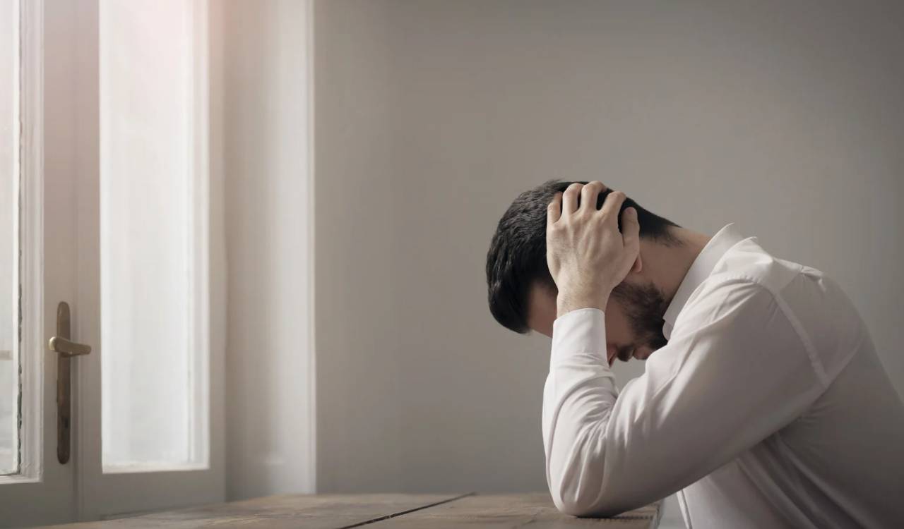 Ein Mann sitzt und fasst sich mit der Hand an den Kopf. Akupressur und das Liegen auf Akupressurmatten hilft gegen Stress und  Stressbelastungsstörungen.